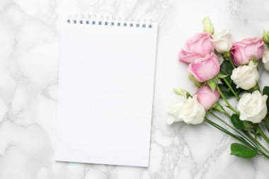 Güzel beyaz ve pembe güller çiçek ve mermer arka planda defter