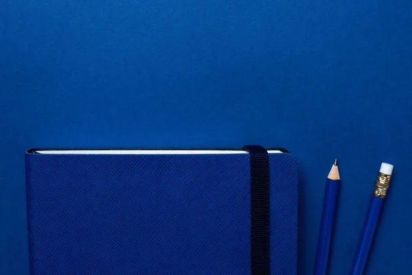 Carnet de bureau bleu et crayon sur fond bleu classique. Couleur pantone tendance 2020 — Photo