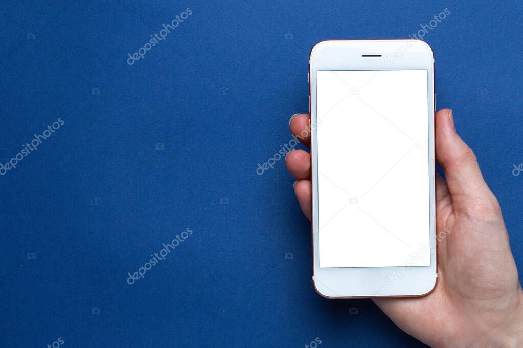 Mobile phone in hand on a classic blue background with copyspace. Trendy Pantone color 2020