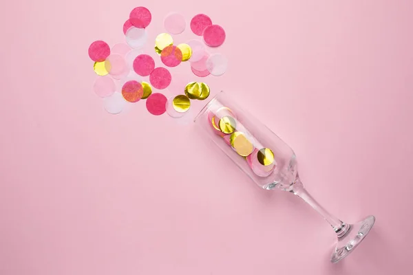 Champagnerglas mit goldenem und rosa Konfetti auf rosa Farbpapier Hintergrund minimalen Stil — Stockfoto