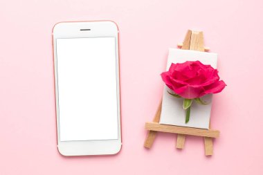 Pembe arka plan, bahar ve yaratıcılık kavramında gül çiçeğiyle resim yapmak için cep telefonu ve tuval