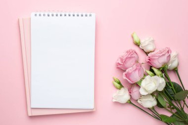 Pastel arka planda güzel beyaz ve pembe güller çiçek ve defter. Bayramlar, sevgililer günü ve kadınlar günü için minimalist kompozisyon.