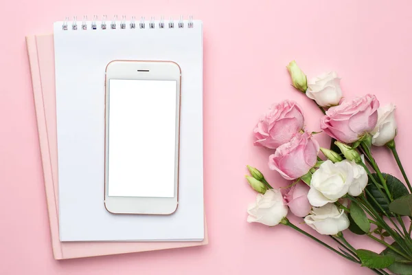 Pastel arka planda pembe ve beyaz güllü cep telefonu. Bayramlar, sevgililer günü ve kadınlar günü için minimalist kompozisyon..