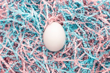 Paskalya yaratıcı kompozisyonu. Paskalya yumurtası, kraft kağıdı, pembe ve mavi dolgu maddesiyle yatıyordu. Asgari bahar kavramı.