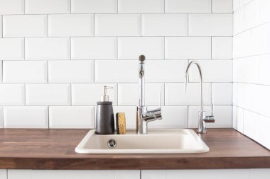 Mutfakta musluk ve lavabo var. Yaslanma, su tasarrufu, bulaşıkları parlak bir İskandinav iç görünümünde yıkama.