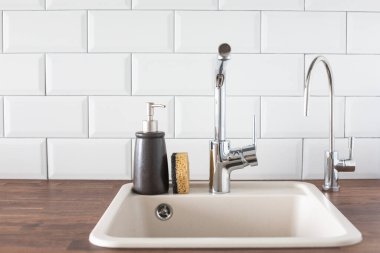 Mutfakta musluk ve lavabo var. Yaslanma, su tasarrufu, bulaşıkları parlak bir İskandinav iç görünümünde yıkama.