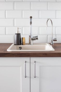 Mutfakta musluk ve lavabo var. Yaslanma, su tasarrufu, bulaşıkları parlak bir İskandinav iç görünümünde yıkama.