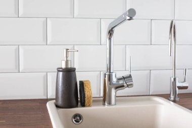 Mutfakta musluk ve lavabo var. Yaslanma, su tasarrufu, bulaşıkları parlak bir İskandinav iç görünümünde yıkama.