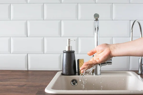 Mutfaktaki bir musluktan kopyalanmış su altında el yıkama. Yaslanma, su tasarrufu, bulaşıkları parlak bir İskandinav iç görünümünde yıkama.