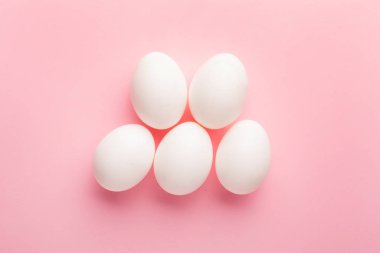 Pembe arka planda beyaz yumurtalar. Paskalya bayramı ve yiyecek konsepti üst görünüm
