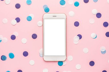Cep telefonu ve mavi, beyaz ve eflatun konfeti pembe renkli kağıt arka planda minimal stil üst görünüm