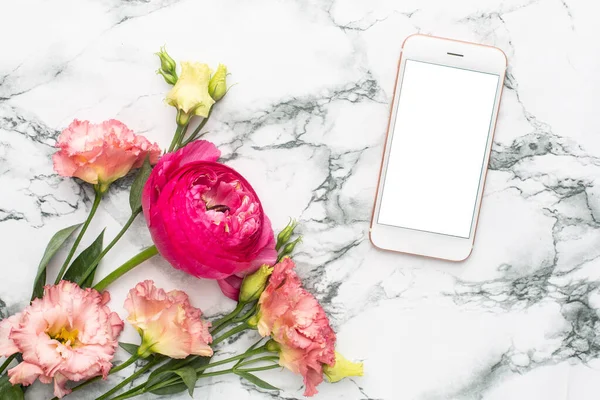 Mobile phone and Ranunculi pink flower bouquet on marble background with copyspace top view