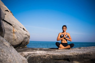Asyalı kadın kumsalda yoga yaparken