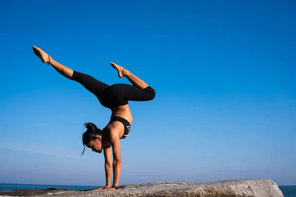 Asian woman doing yoga on the beach