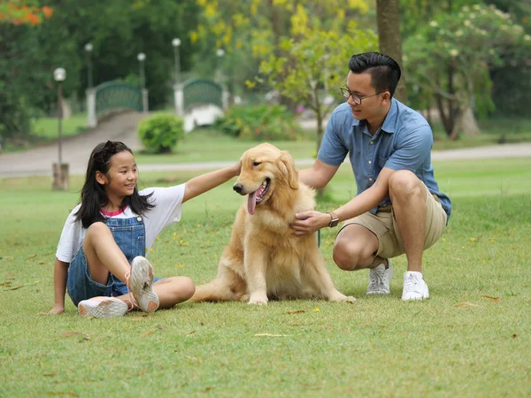 Asiático hombre y chica con perro dorado retriever en parque — Foto de Stock
