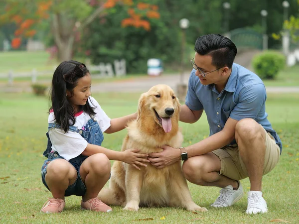 Asiático homem e menina com cão golden retriever no parque — Fotografia de Stock