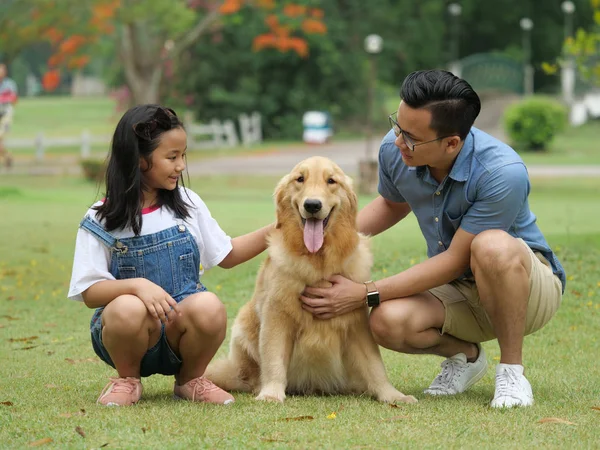 Asian man and girl with dog golden retriever in park