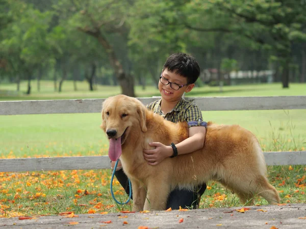Ασίας αγόρι παίζει με κουτάβι σκυλί χρυσή Μπαρμπέ στο πάρκο — Φωτογραφία Αρχείου