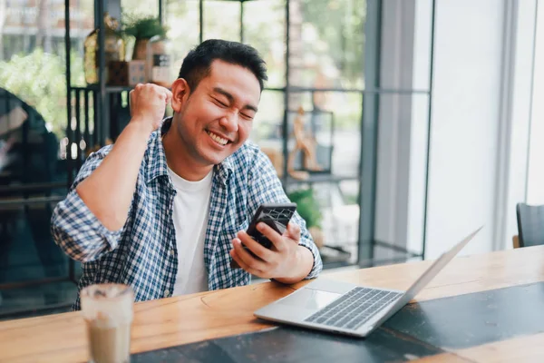 Азиатский молодой человек в голубой рубашке работает с ноутбуком и м — стоковое фото