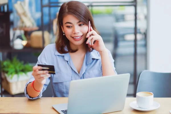 Asyalı kadın kredi kartı ve dizüstü compu ile cep telefonu kullanarak