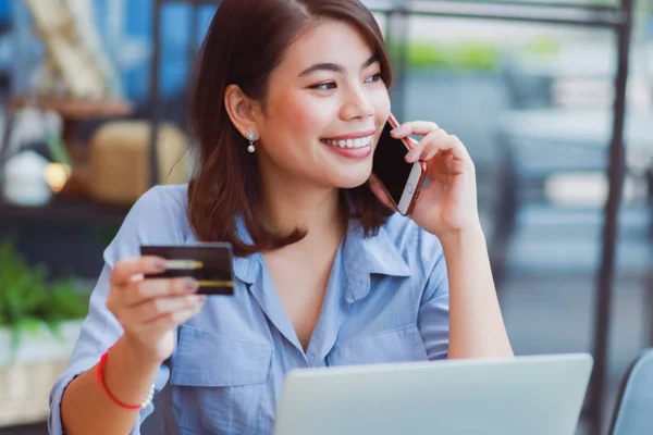 Asiatisk kvinne som bruker mobiltelefon med kredittkort og bærbar datamaskin – stockfoto