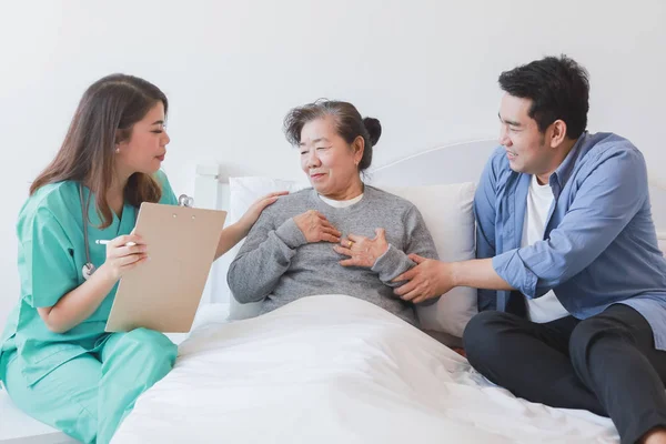 Ázsiai idős nő az ágyon orvos és fia a ringyók — Stock Fotó