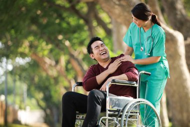 Park hastanesinde tekerlekli sandalyede oturan Asyalı genç adam. 