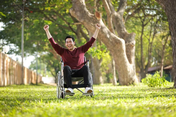 Asiático joven hombre sentado en la silla de ruedas en el parque hospital — Foto de Stock
