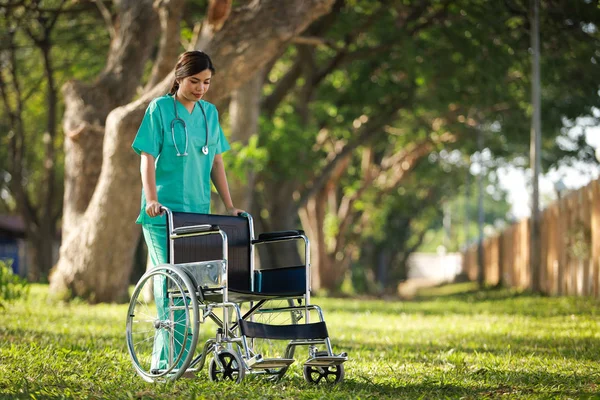 Asiática mujer en doctor uniforme con silla de ruedas en hospital park o — Foto de Stock