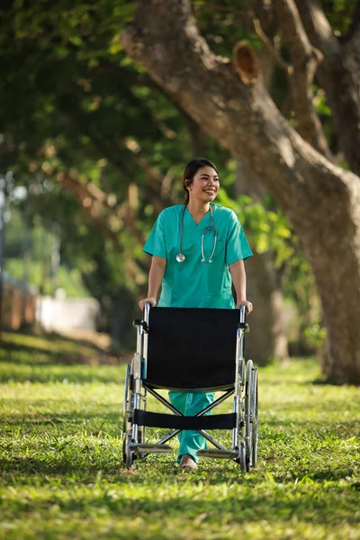 Asiática mujer en doctor uniforme con silla de ruedas en hospital park o — Foto de Stock