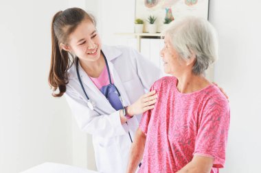 Asyalı yaşlı hasta kadın klinik hastanesinde tıp doktoru kadınlarla konuşuyor.