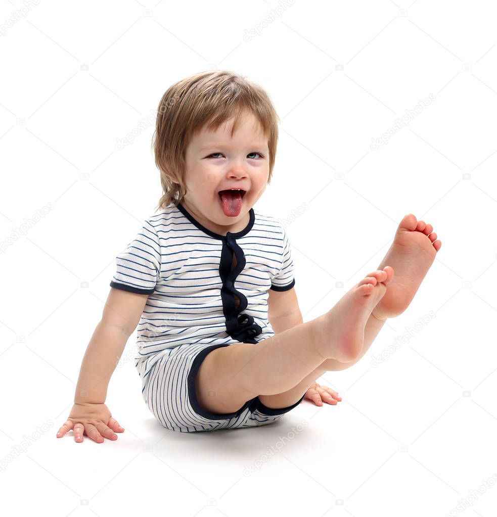 A handsome baby 1.5 years sits propelling its feet. Isolated on a white background.