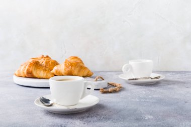 Beyaz bardak kahve ve kruvasan