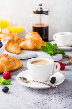Beyaz bardak kahve ve kruvasan