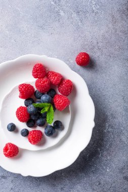 Taze yaban mersini ve ahududu beyaz tabakta aldı