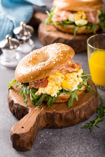 Bagels with scrambled eggs, rucola and fried bacon — Stock Photo, Image