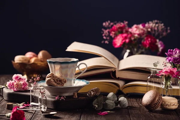 Taza de café, libros antiguos y flores de clavel rosa — Foto de Stock