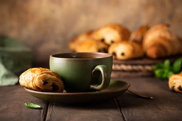 Green cup of tea with mini chocolate bun — Stock Photo, Image