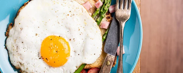 Завтрак или обед с яичницей, хлебными тостами, зеленой спаржей, помидорами и беконом — стоковое фото
