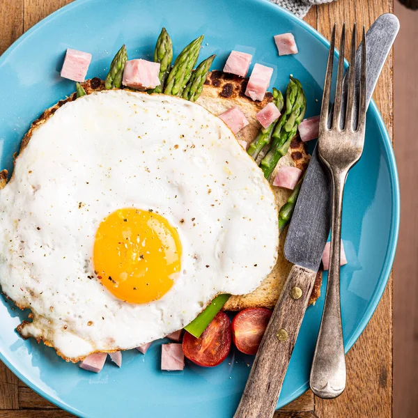 Śniadanie lub obiad z jajkiem smażonym, tostem chlebowym, zielonymi szparagami, pomidorami i bekonem — Zdjęcie stockowe