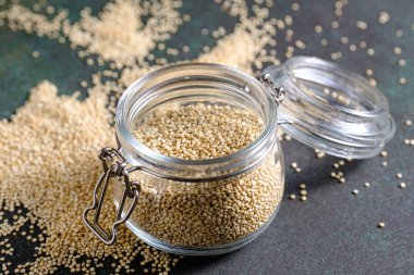 Yeşil kırsal arka planda cam kavanozda beyaz çiğ kinoa.