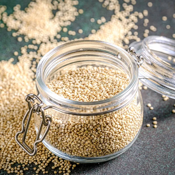 White raw quinoa in glass jar on green rustic background. — Stock Photo, Image