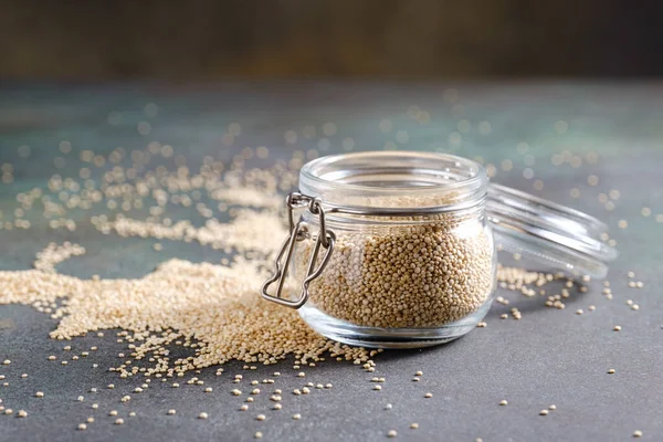 Branco quinoa crua em frasco de vidro no fundo rústico verde . — Fotografia de Stock