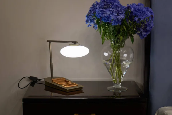 Lampa, nattduksbord och blommor — Stockfoto