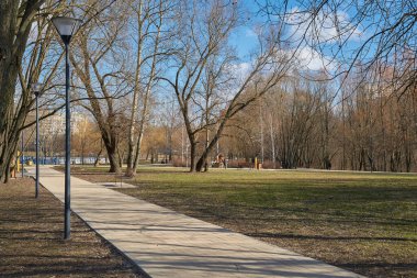 Moskova 'nın Yuzhnoye Medvedkovo ilçesinde bahar aylarında pedistian yürüyüş yolu ve sokak lambalarıyla park manzarası