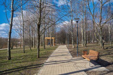 Moskova 'nın Yuzhnoye Medvedkovo İlçesi İlkbaharda parkta yaya geçidi, bank ve ahşap pergola
