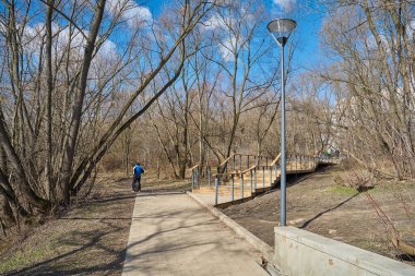 Moskova 'nın Yuzhnoye Medvedkovo ilçesinde, pedistian yürüyüş yolu ve ahşap merdivenlerle ilkbaharda parkın manzarası