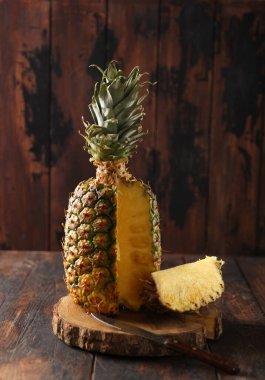 Egzotik meyve. Ananas dilimi ve eski ahşap arka planda bir bıçak. Taşralı. Arkaplan resmi, alanı kopyala