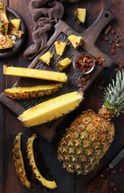 Egzotik meyve. Tam ananas ve bir dilim ananas, kuru üzümler ve eski ahşap arka planda bir bıçak. Taşralı. Arkaplan resmi