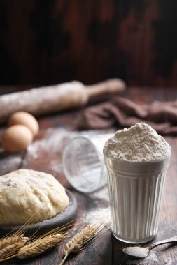 Fırın. Pişirme hazırlığı. Hamur, un, çavdar kulağı, eski ahşap bir arka planda kaşık içinde yuvarlanan iğne ve şeker. Taşralı. Arkaplan resmi, alanı kopyala